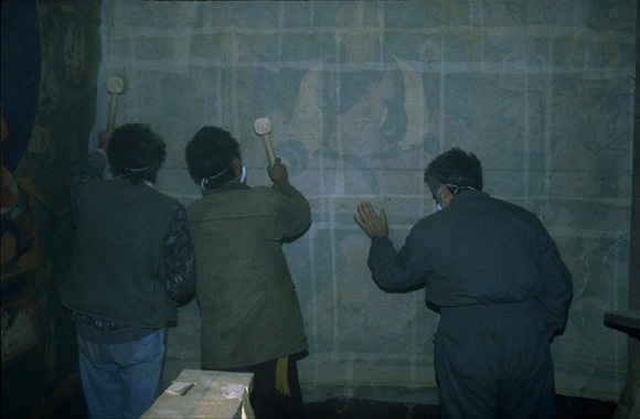 The team loosens a mural from its underlying clay by hitting the

gauze-covered mural with mallets.

