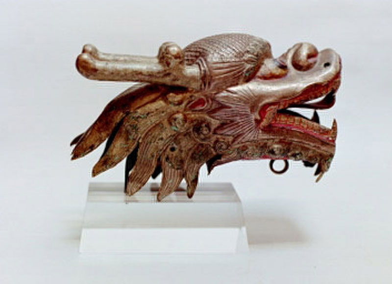 A gilt copper repousse head of a horned dragon