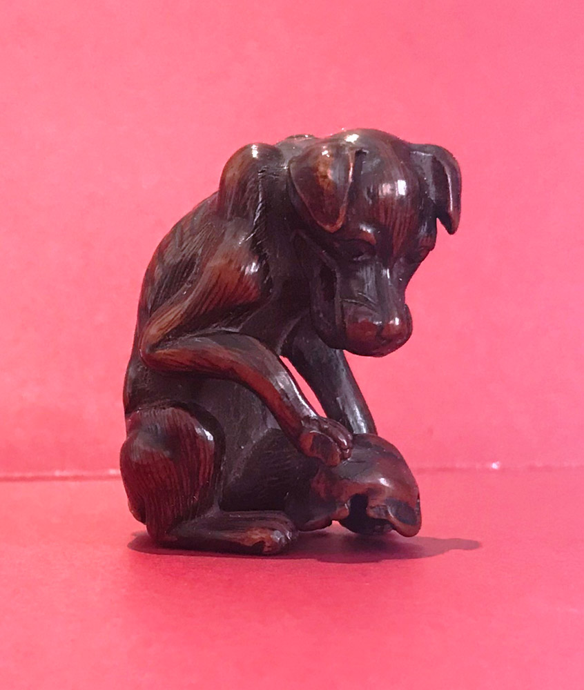 Wood netsuke of a Yama-inu (wild dog) with a skull