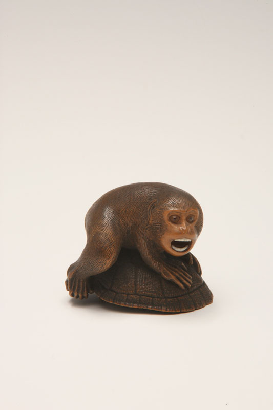 Netsuke of a monkey with a turtle biting his foot